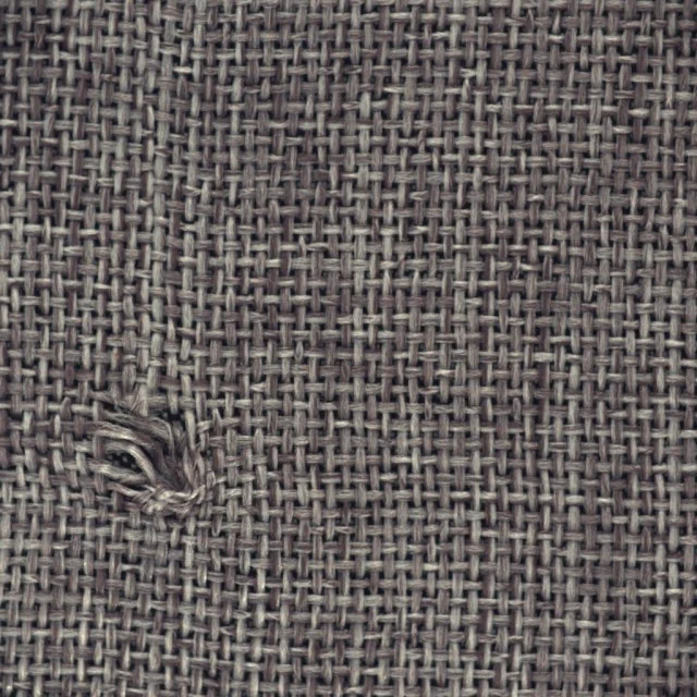Tejido de alfombra gris con un nudo de hilos sueltos en la parte inferior izquierda.
